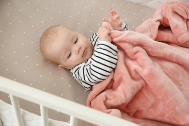 Photo of Cute baby girl in crib. Bedtime schedule