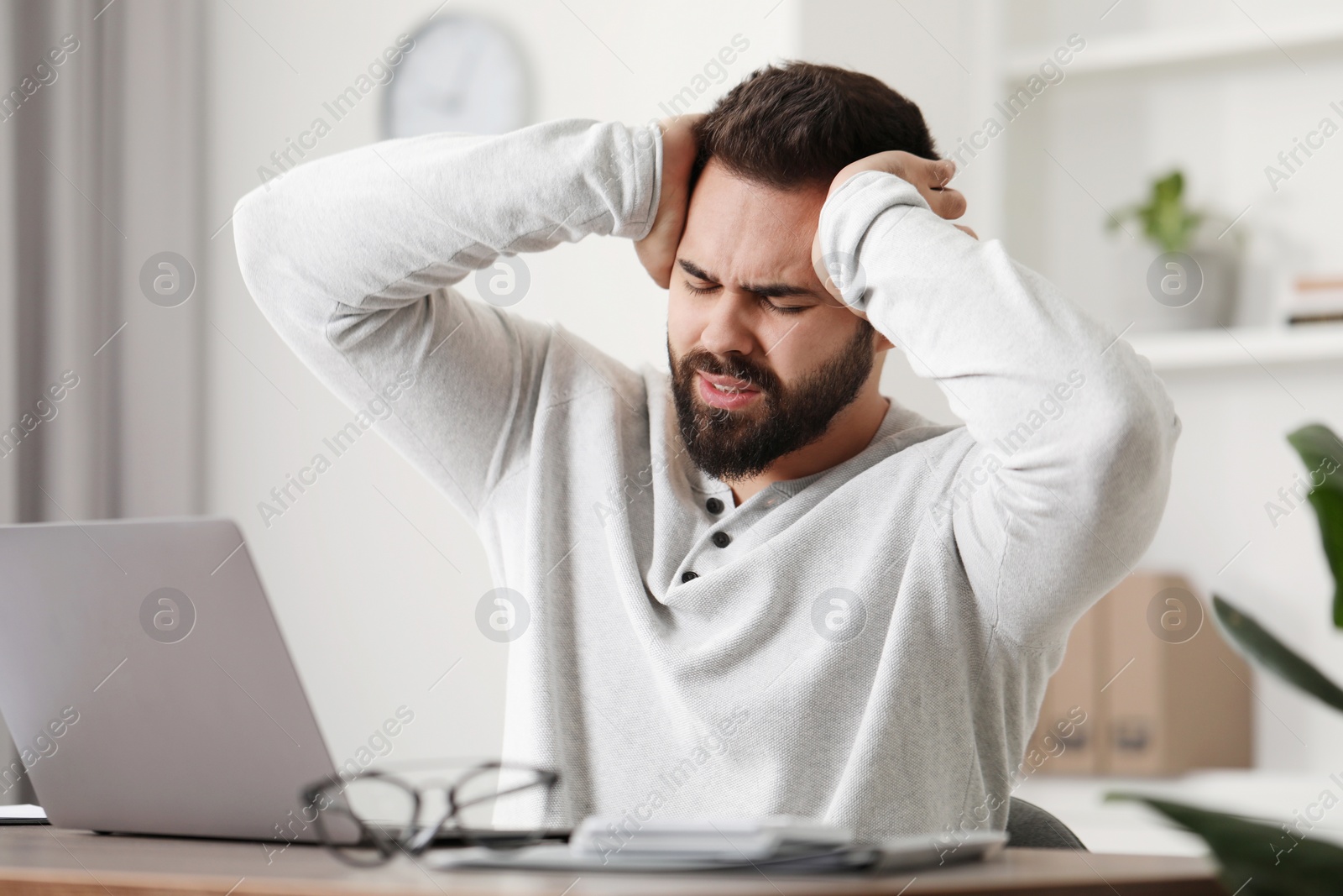 Photo of Man suffering from headache at workplace in office