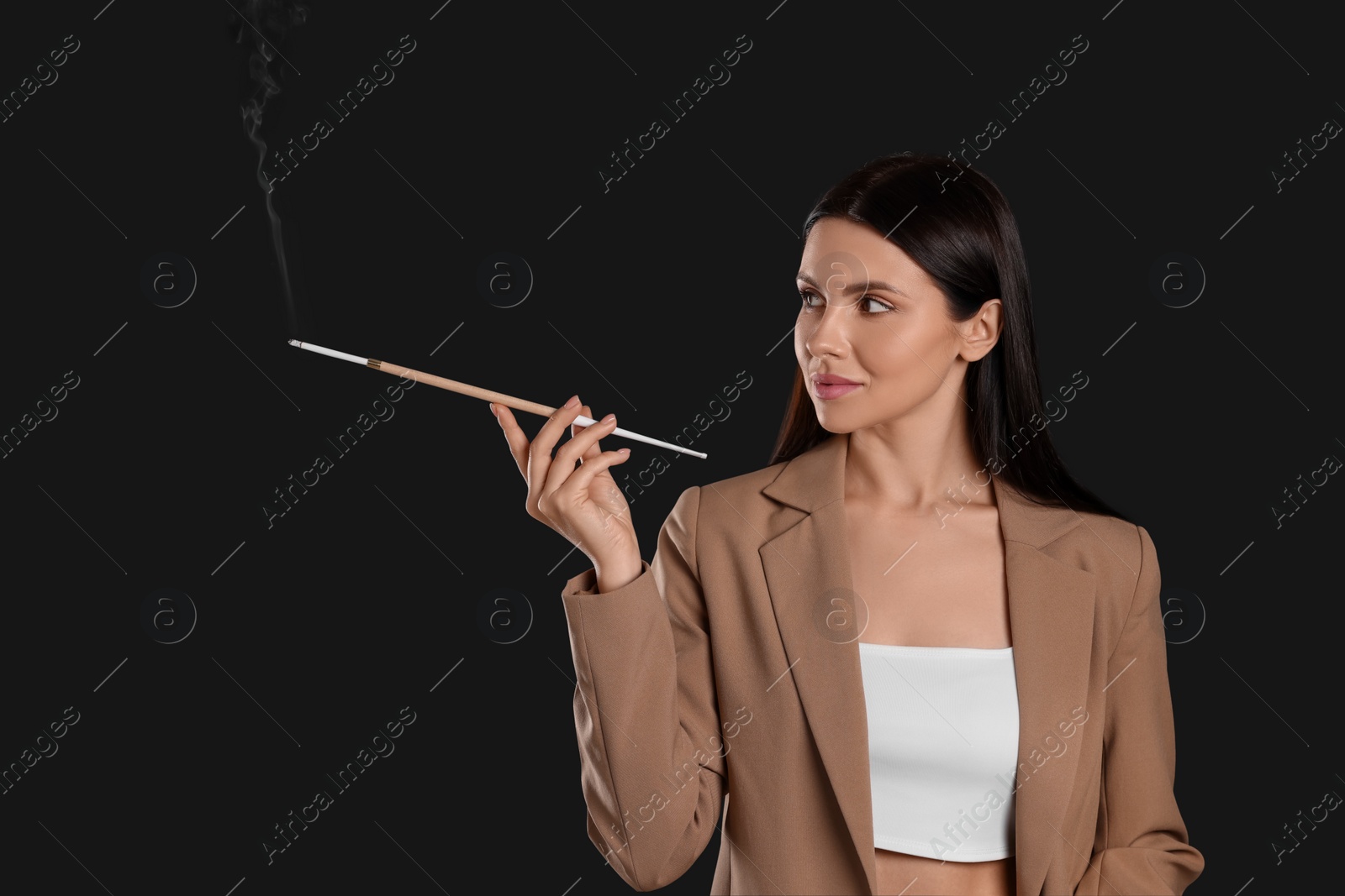 Photo of Woman using long cigarette holder for smoking on black background