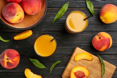 Natural peach juice and fresh fruits on black wooden table, flat lay
