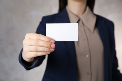 Photo of Woman holding white business card on grey background, closeup