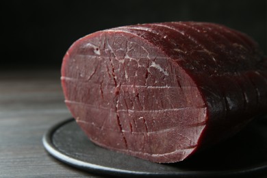 Photo of Tasty bresaola on wooden table, closeup view
