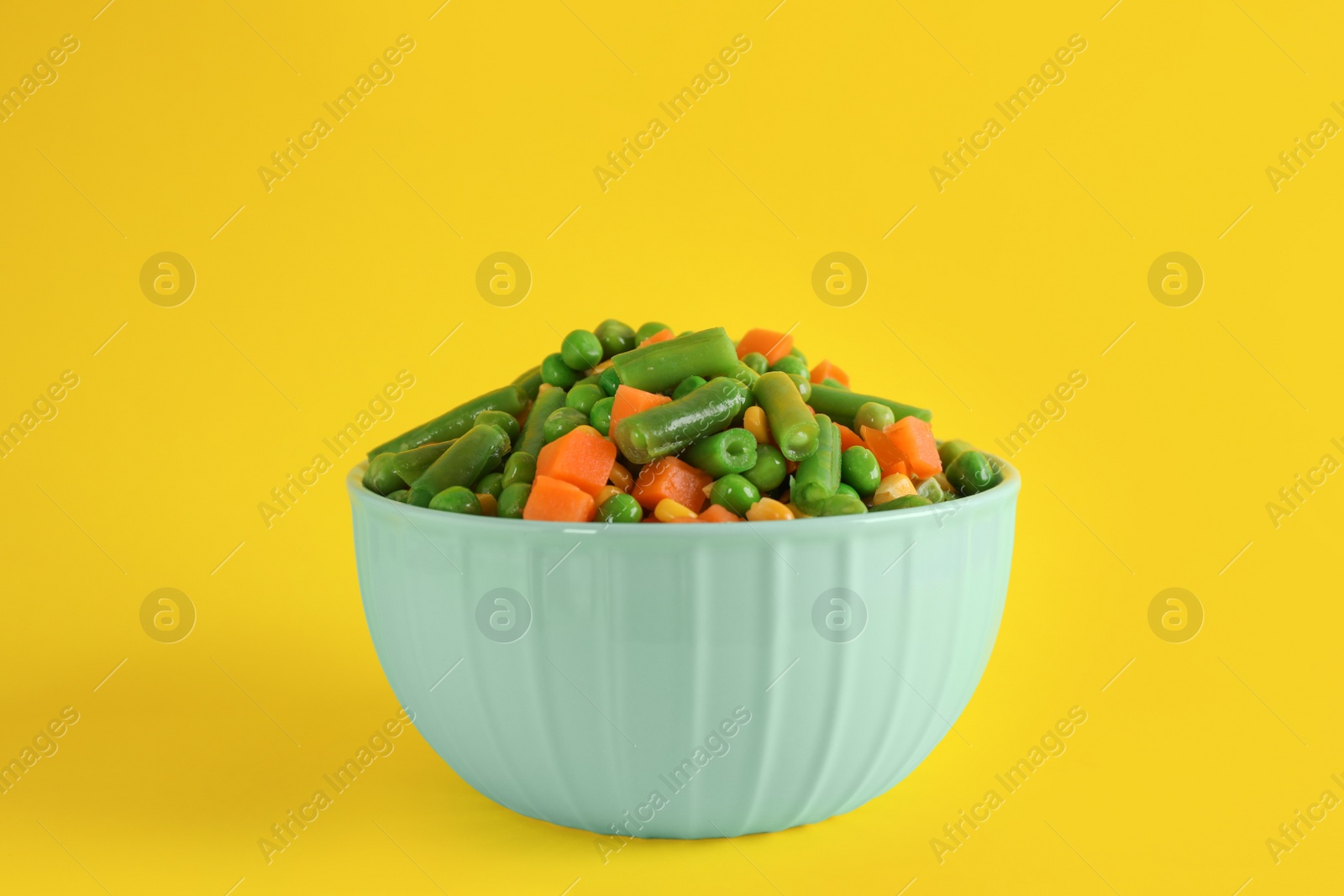 Photo of Mix of fresh vegetables in bowl on yellow background