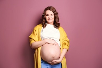 Young pregnant woman in casual clothes on color background