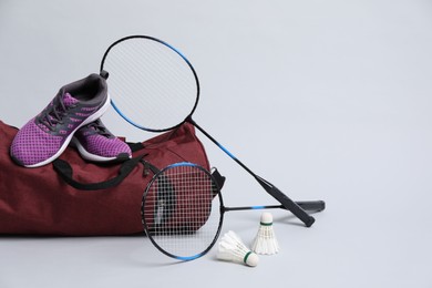 Photo of Feather badminton shuttlecocks, rackets, bag and sneakers on gray background