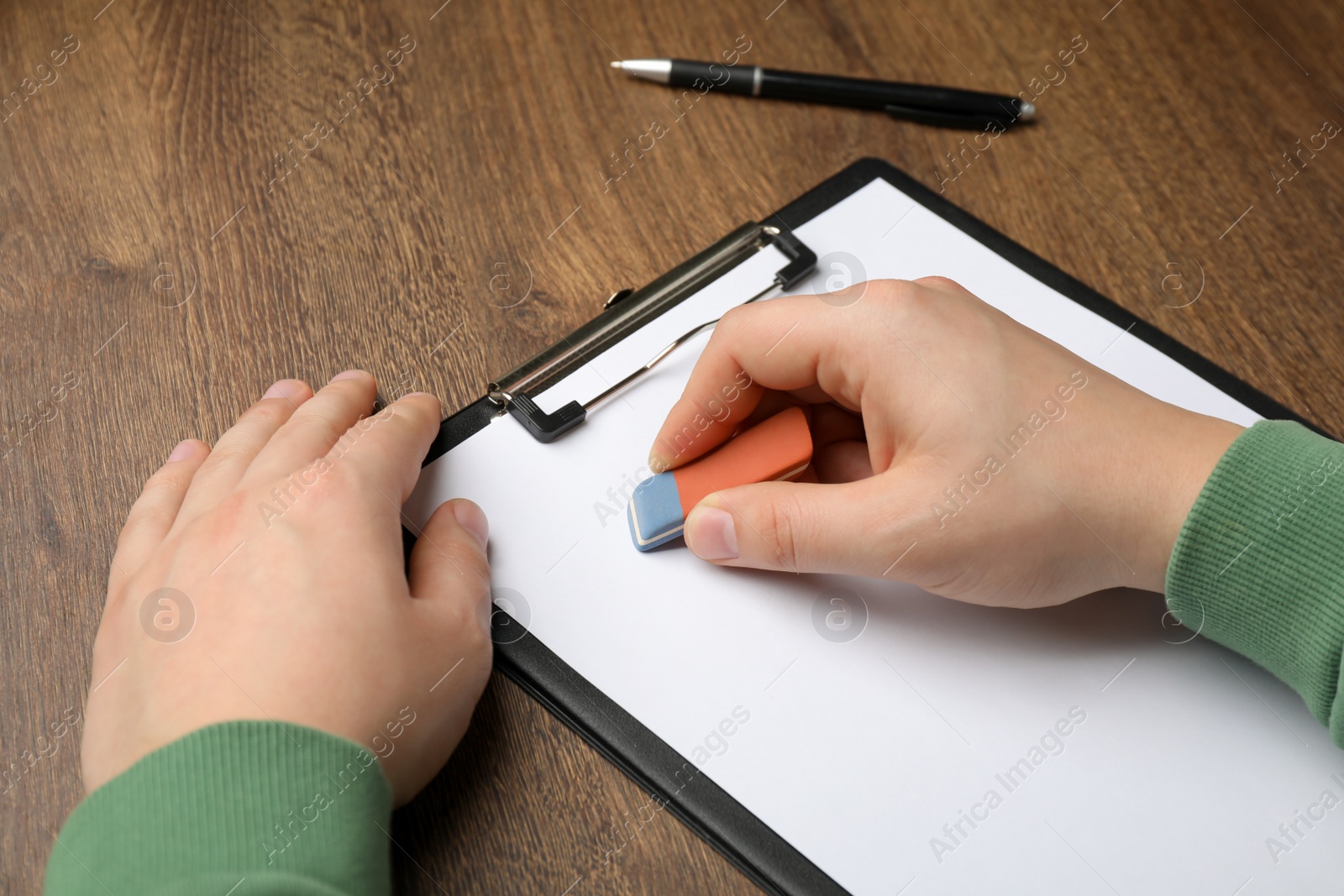 Photo of Man erasing something on paper at wooden table, closeup