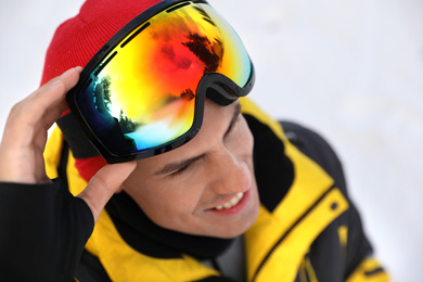 Photo of Handsome man at ski resort, focus on goggles. Winter sports equipment