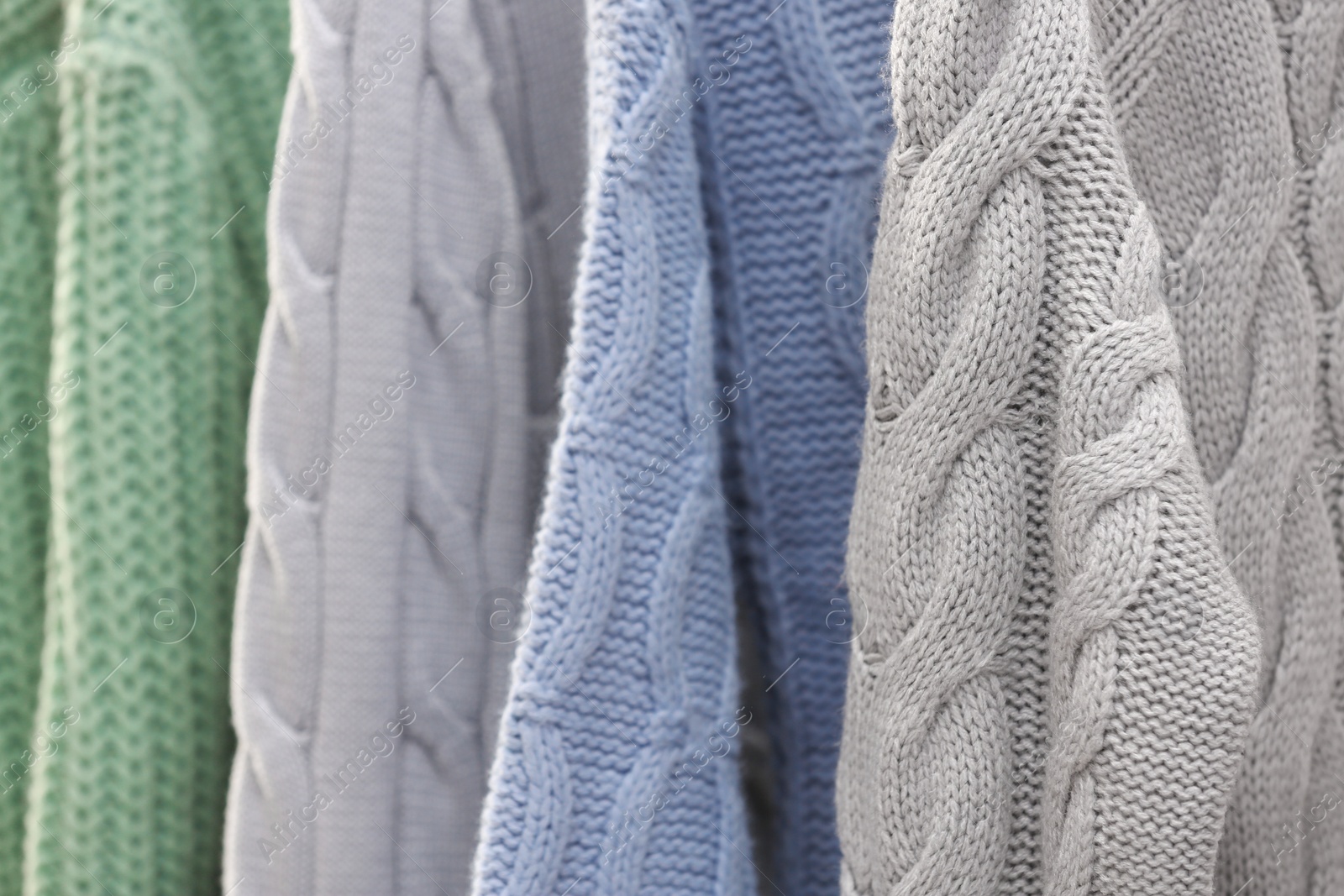 Photo of Collection of warm sweaters as background, closeup