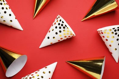 Photo of Bright party hats on red background, flat lay