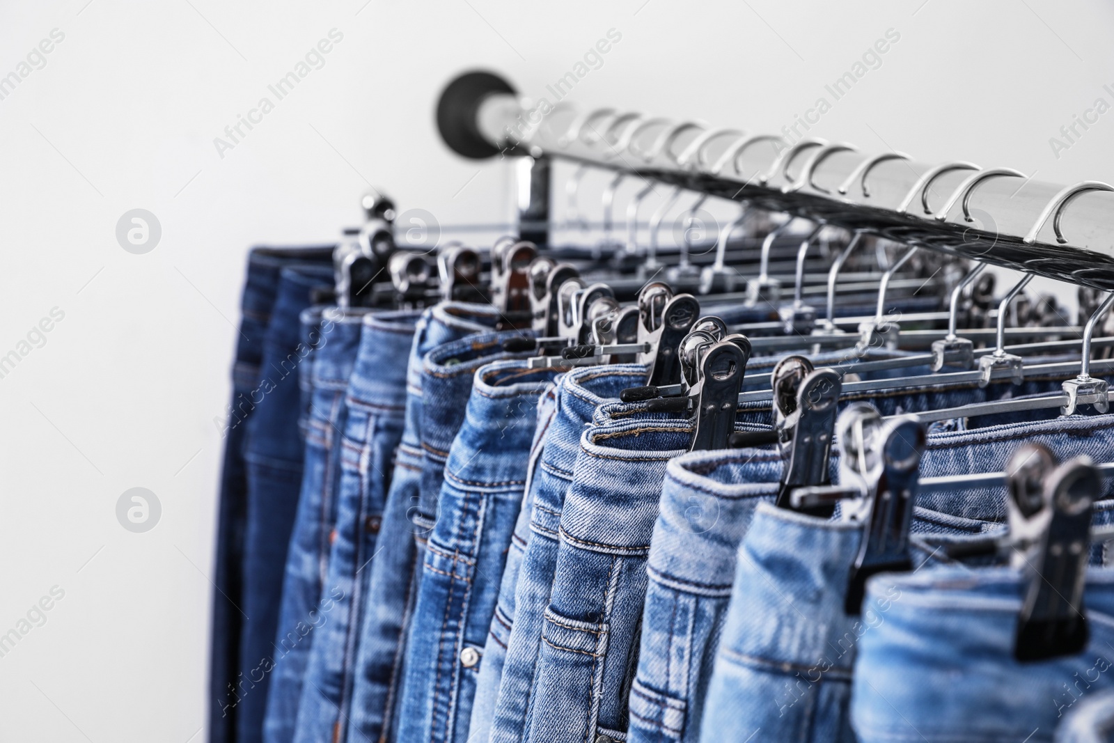 Photo of Rack with different jeans on light background, closeup