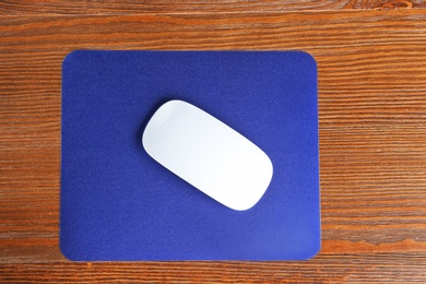 Blank pad and wireless computer mouse on wooden background, top view