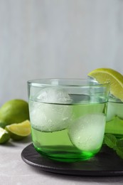 Photo of Delicious cocktail with lime and ice balls on grey table, space for text
