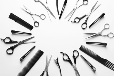 Photo of Frame made of scissors and other hairdresser's accessories on white background, top view. Space for text