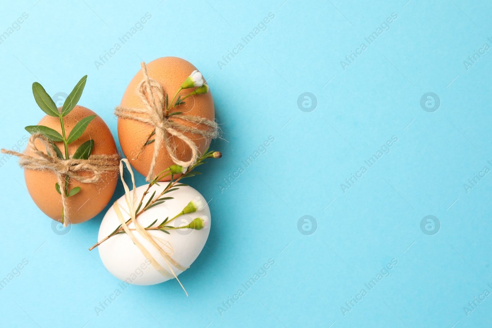 Photo of Festively decorated chicken eggs on light blue background, flat lay with space for text. Happy Easter