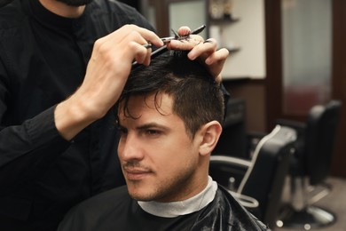 Photo of Professional hairdresser making stylish haircut in salon, closeup
