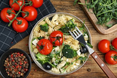 Photo of Bowl of delicious pasta with tomatoes, broccoli and cheese on wooden table, flat lay