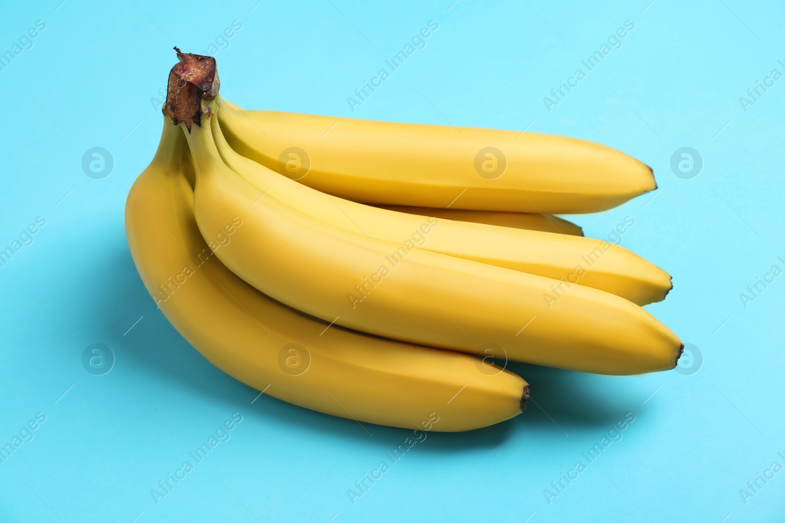 Photo of Bunch of ripe yellow bananas on turquoise background