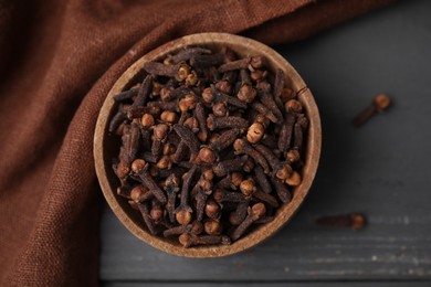 Photo of Aromatic cloves in bowl on grey wooden table, top view