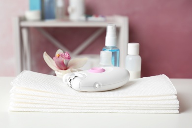 Modern epilator and napkins on table