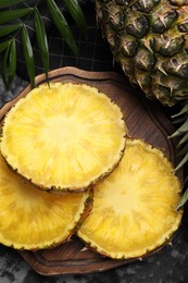 Photo of Slices of tasty ripe pineapple on black table, flat lay