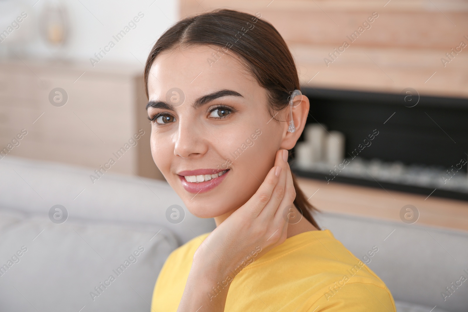 Photo of Young woman with hearing aid at home