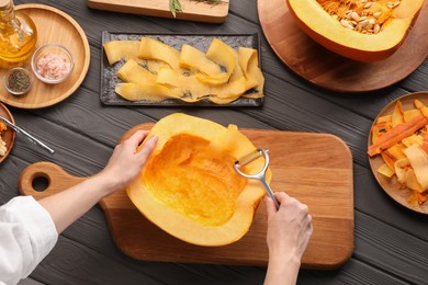 Photo of Woman slicing fresh pumpkin at grey wooden table, top view