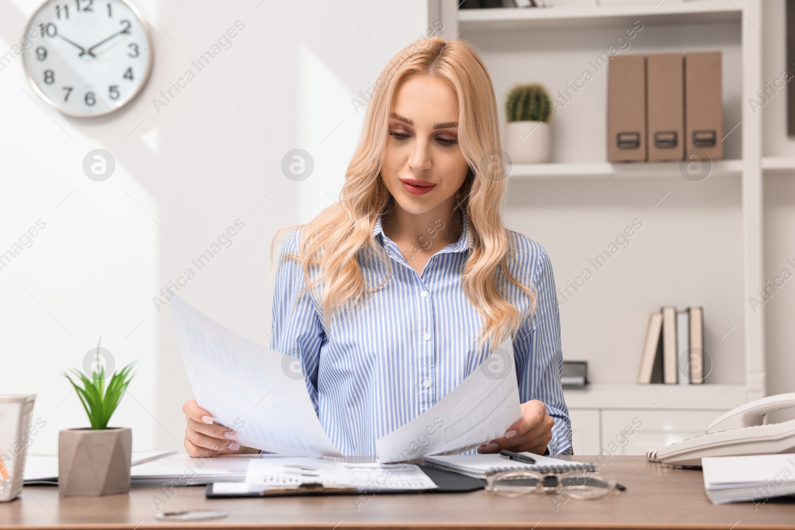 Photo of Secretary with documents at table in office