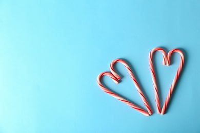 Couple of sweet hearts made with candy canes on color background, top view. Space for text