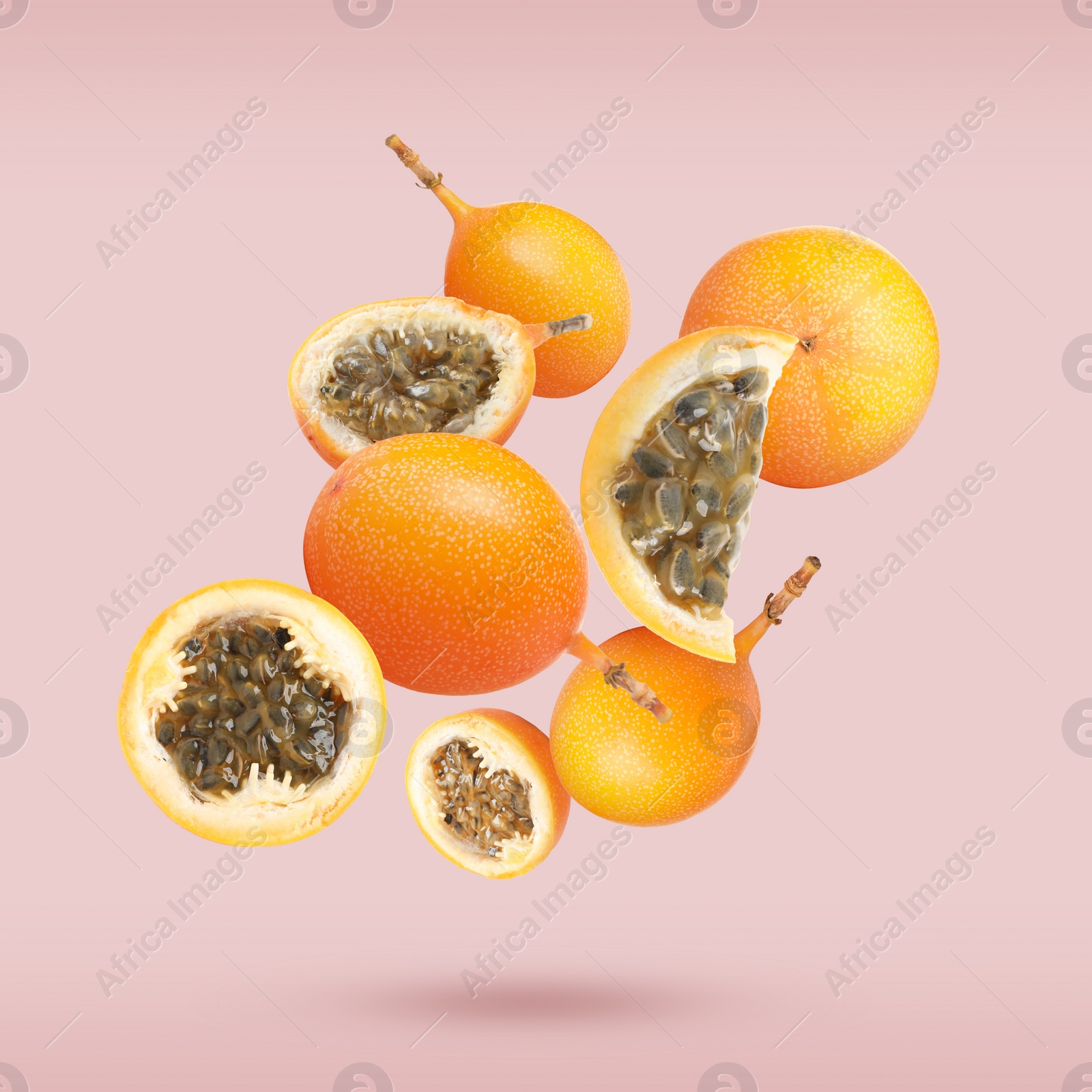 Image of Delicious ripe granadillas falling on pink background