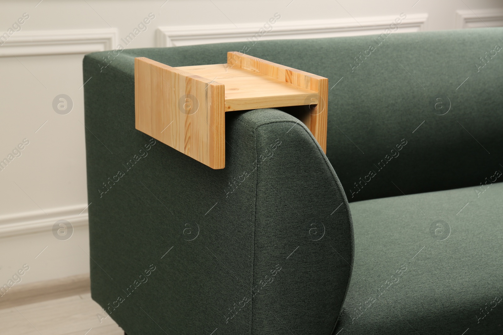 Photo of Wooden armrest table on sofa in room. Interior element