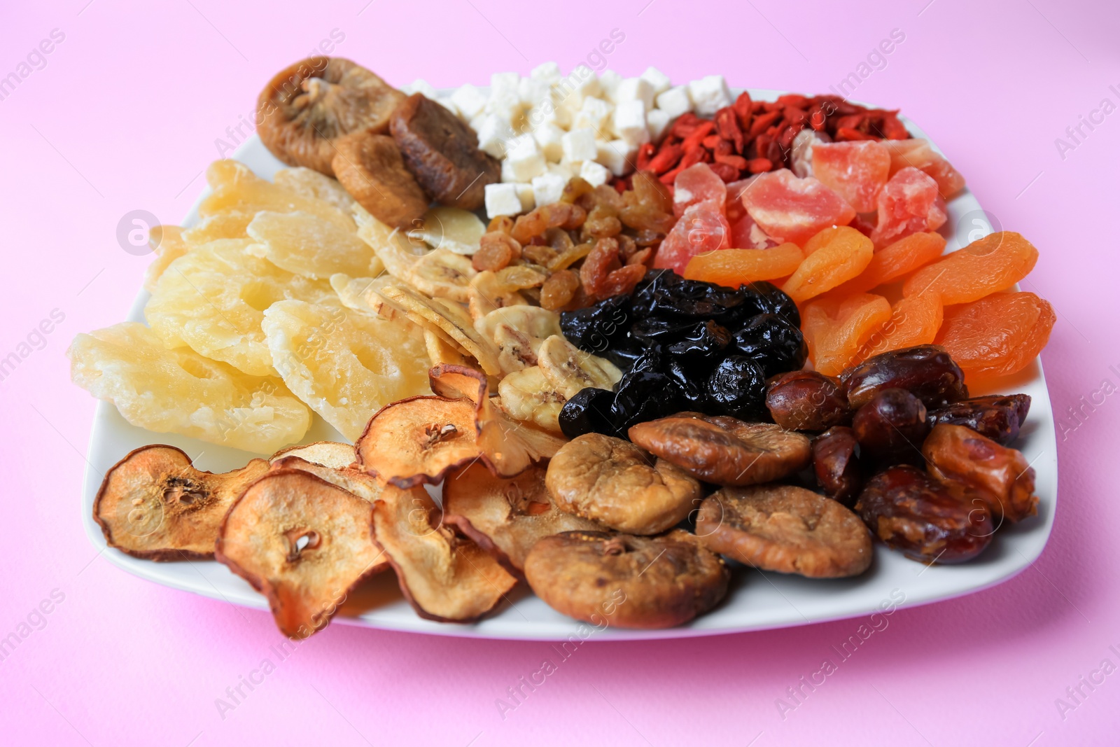 Photo of Plate with different dried fruits on violet background, closeup