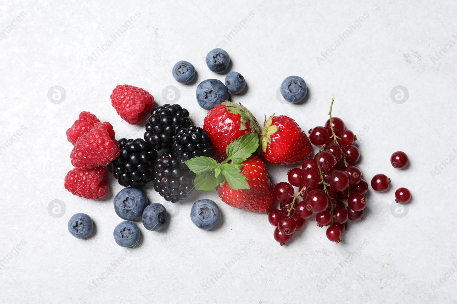 Photo of Many different fresh ripe berries on white textured table, flat lay