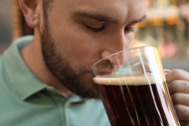 Handsome man with cold kvass outdoors, closeup. Traditional Russian summer drink