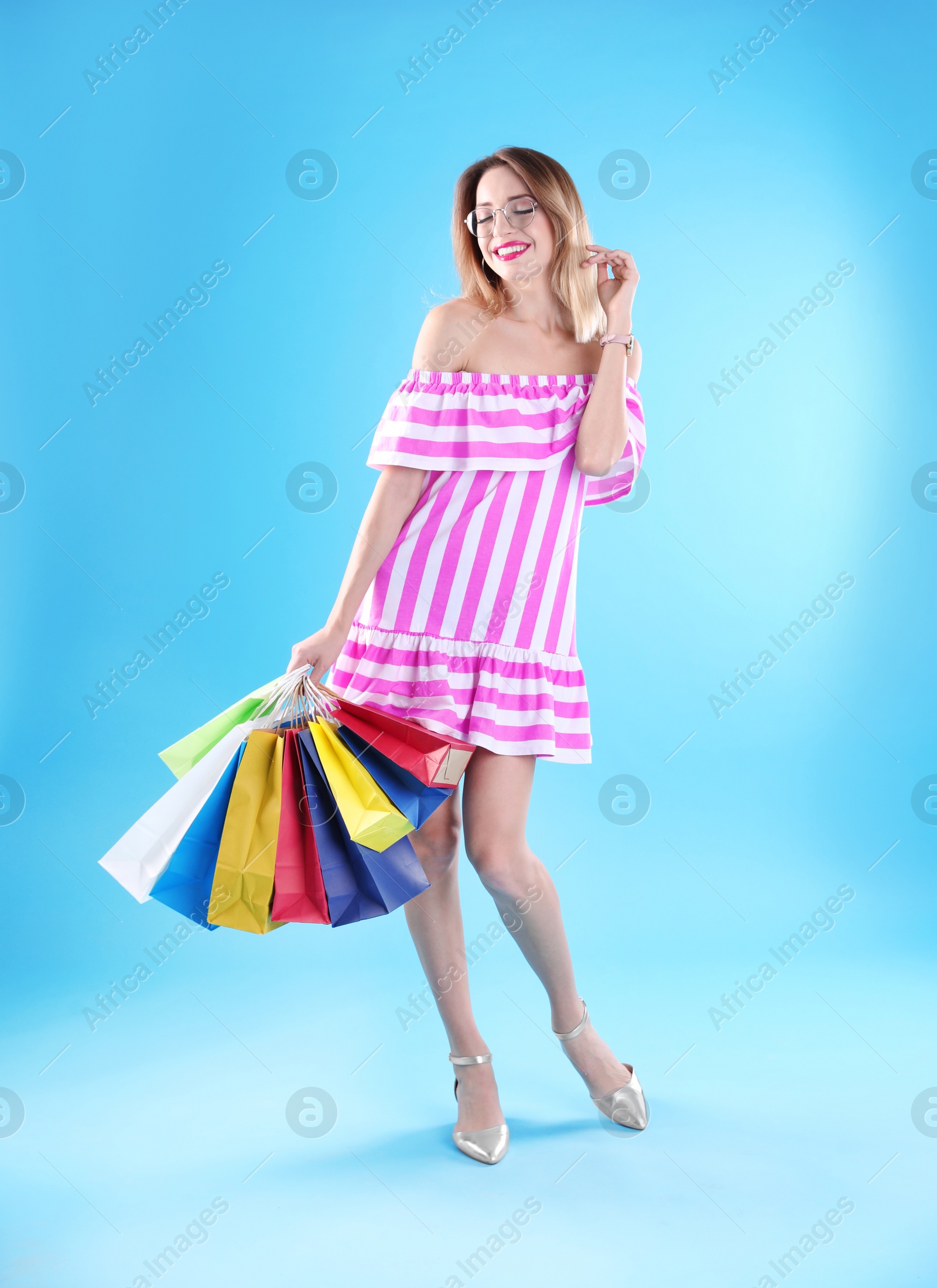 Photo of Beautiful young woman with shopping bags on color background