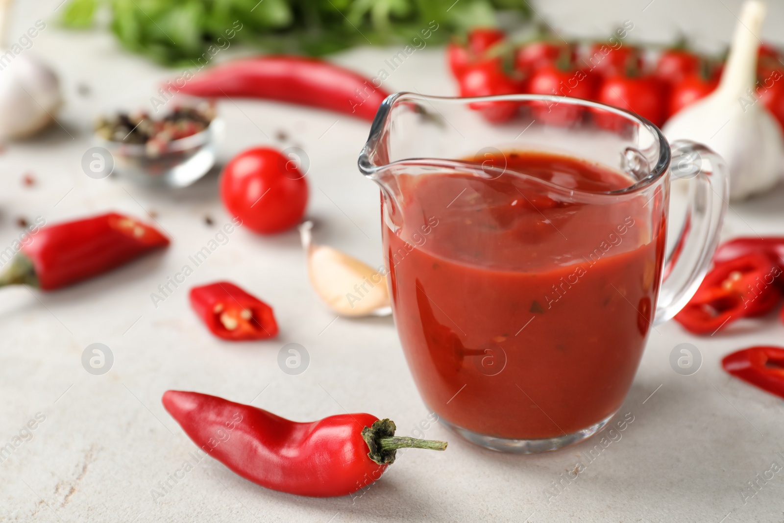 Photo of Jug with spicy chili sauce on light table