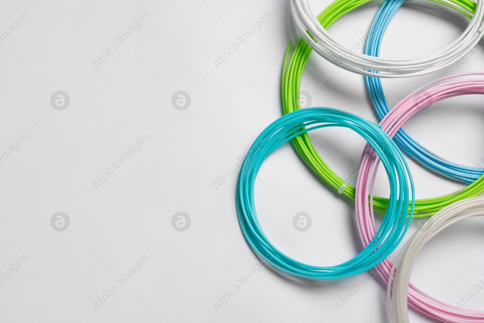 Photo of Colorful plastic filaments for 3D pen on white background, flat lay. Space for text