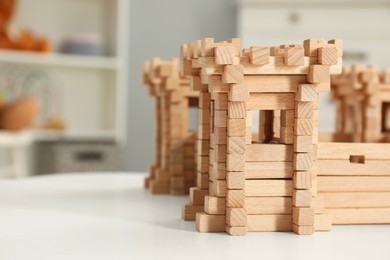 Photo of Wooden fortress on white table indoors, space for text. Children's toy