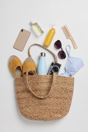 Photo of Wicker bag, smartphone and beach accessories on white background, flat lay