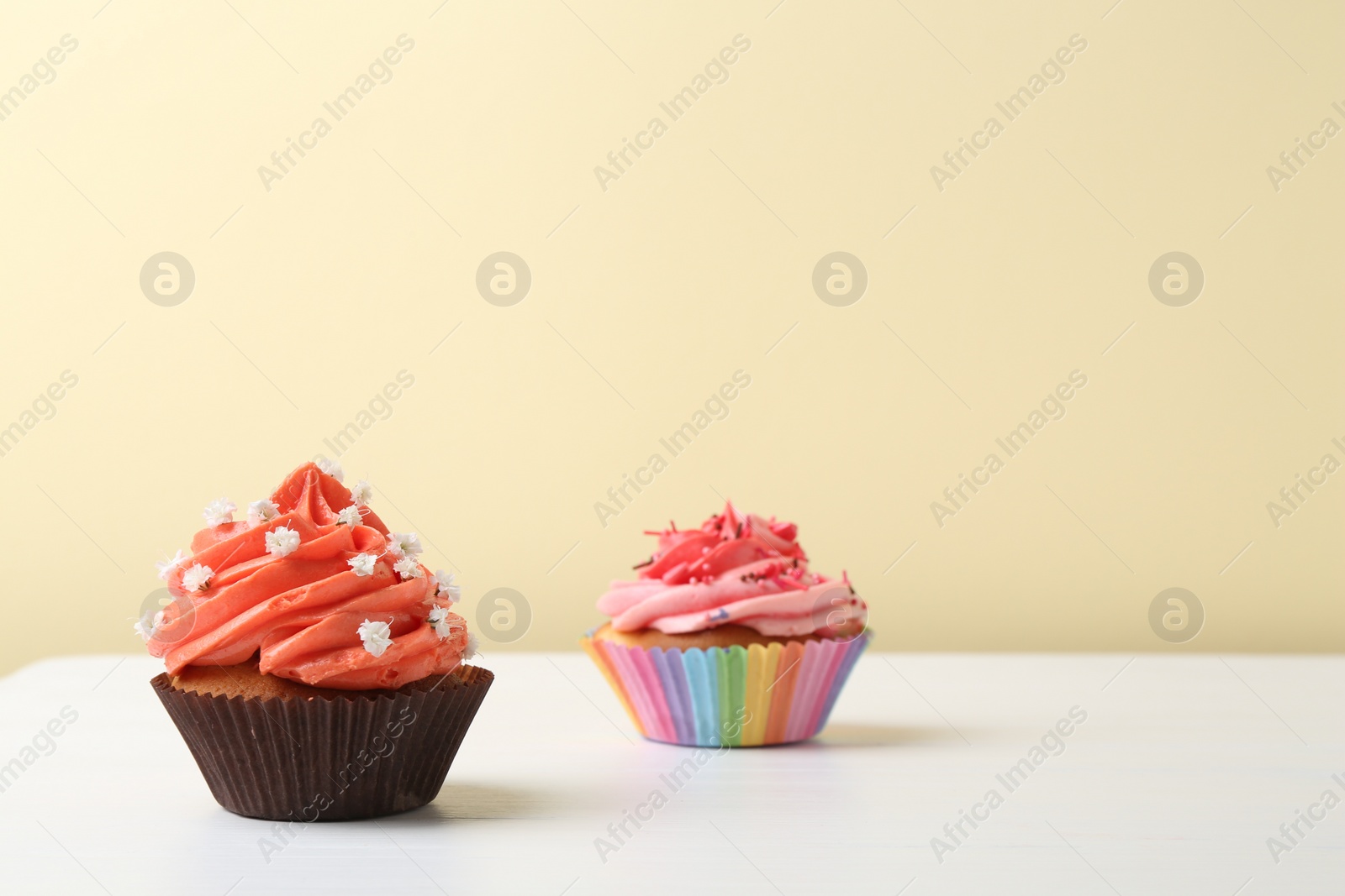 Photo of Delicious cupcake with bright cream on white wooden table. Space for text