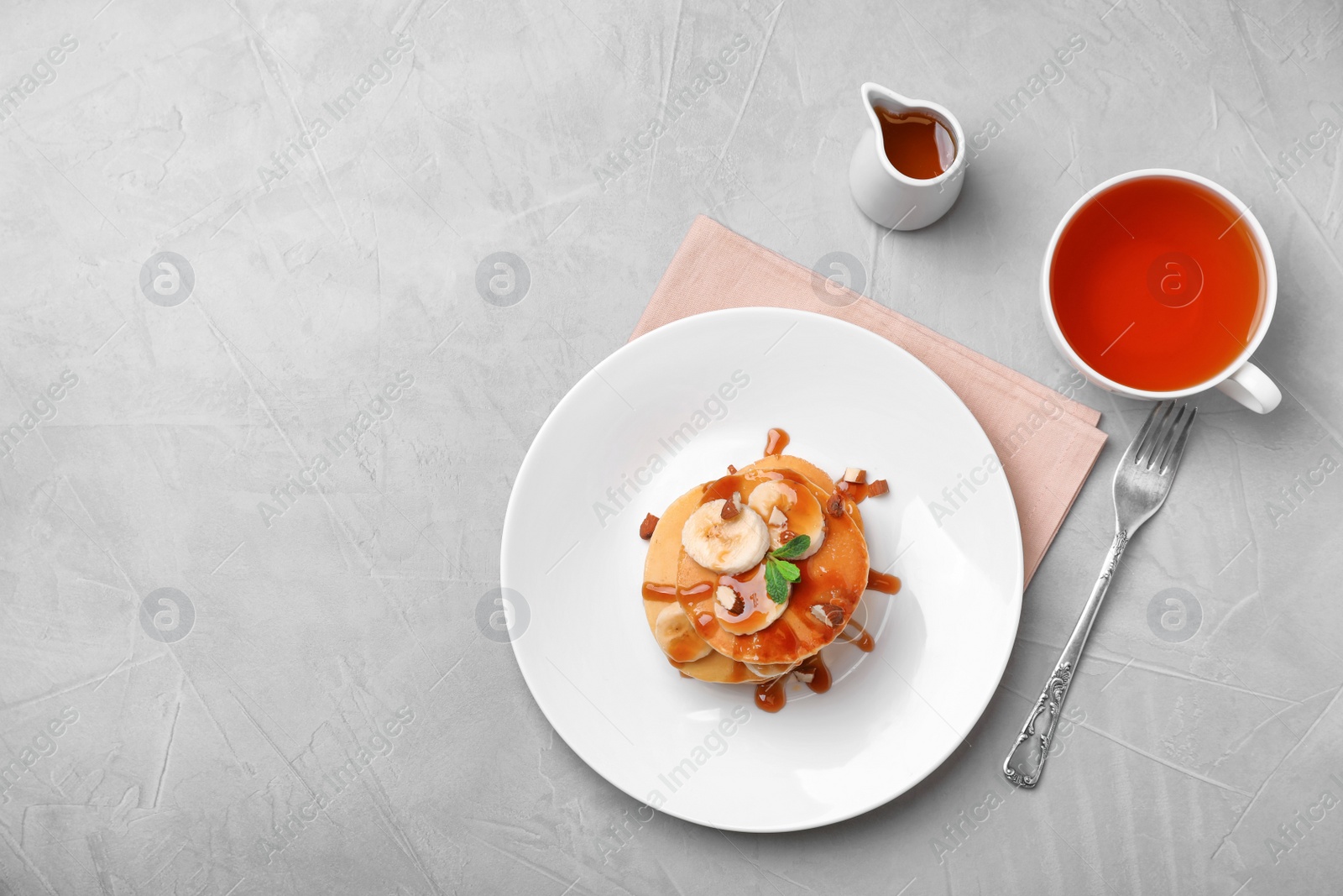 Photo of Flat lay composition with tasty pancakes and cup of tea on grey background