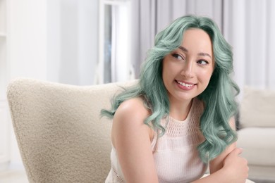 Trendy hairstyle. Young woman with colorful dyed hair at home. Space for text