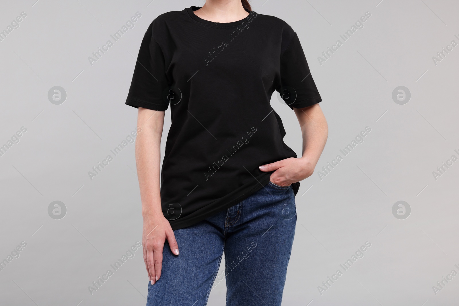 Photo of Woman in stylish black t-shirt light grey on background, closeup