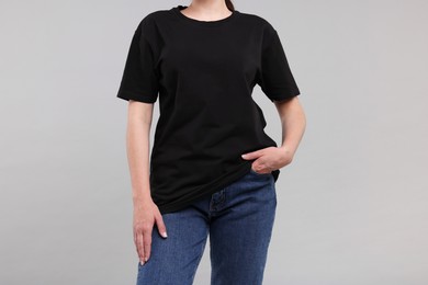 Photo of Woman in stylish black t-shirt light grey on background, closeup