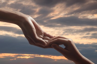 Image of Godparent with child and beautiful sky with clouds at sunset on background, closeup