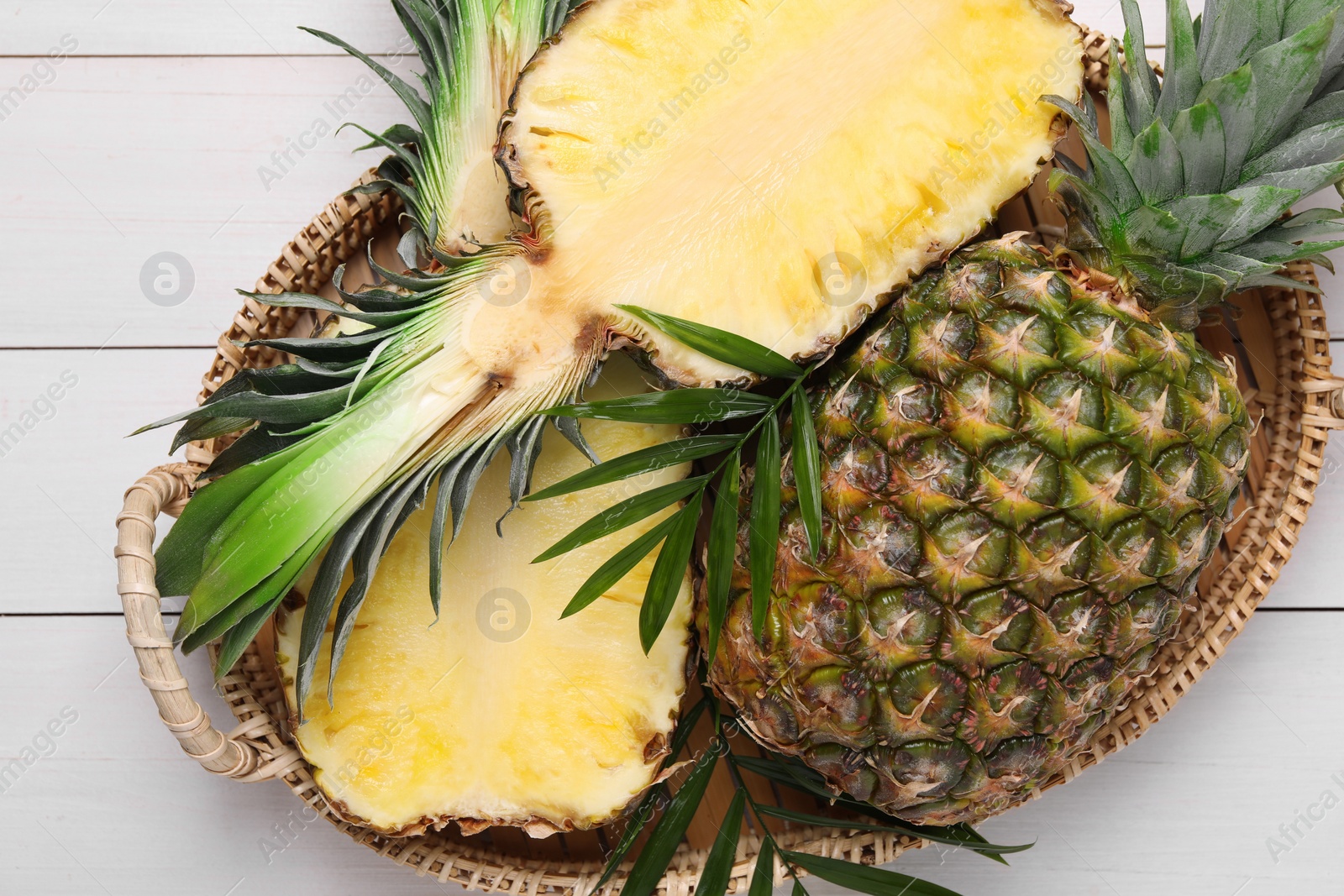 Photo of Whole and cut ripe pineapples on white wooden table, top view