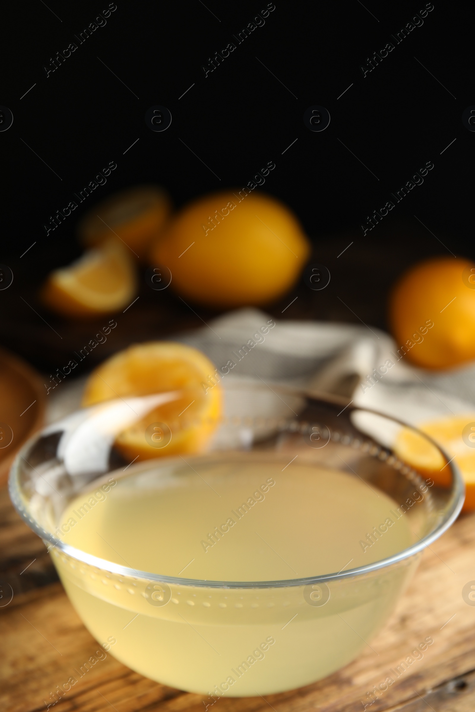 Photo of Freshly squeezed lemon juice in glass bowl on wooden table