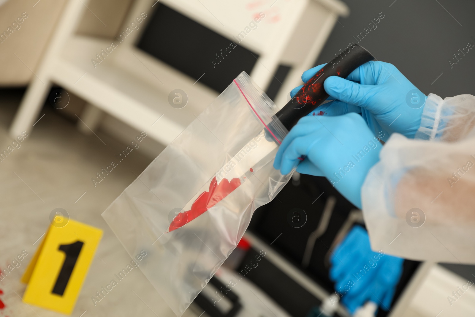 Photo of Investigator in protective gloves working with evidence indoors, closeup. Crime scene