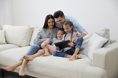 Photo of Family with tablet sitting on comfortable sofa in living room