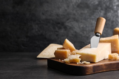 Photo of Parmesan cheese with knife on grey table. Space for text