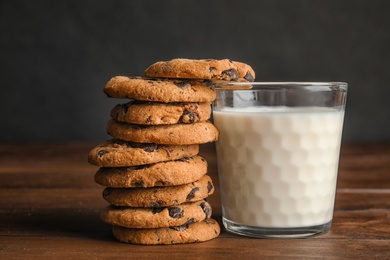 Tasty chocolate chip cookies and glass of milk on wooden table